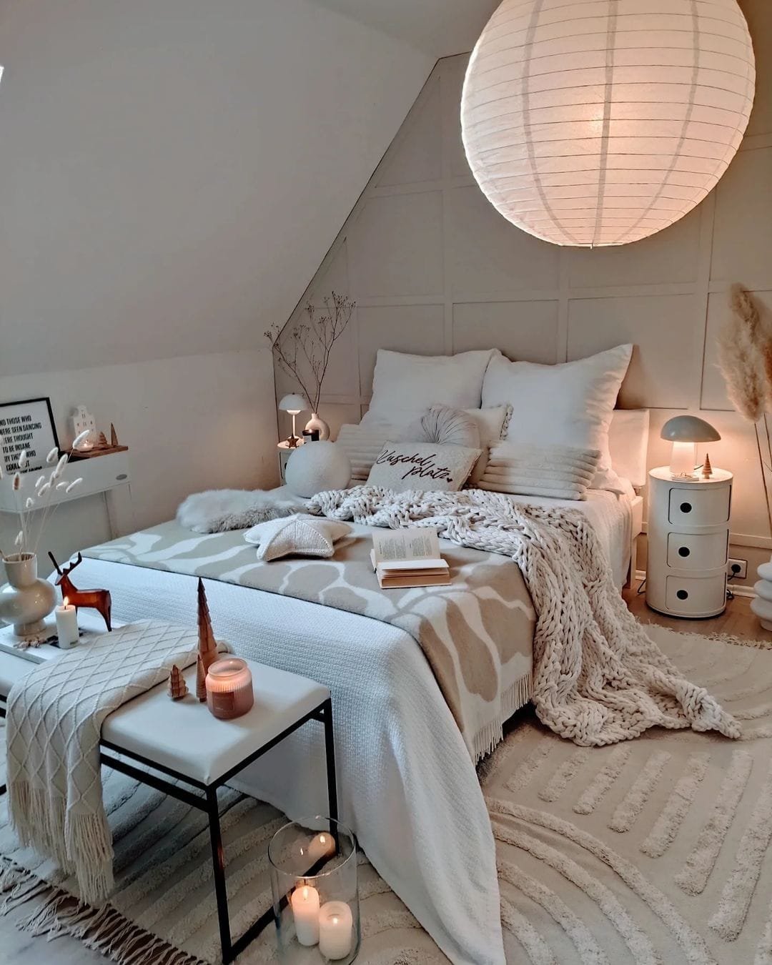 a bed styled with pillows and a knit blanket and an end bench styled with a throw, candles, and other accents showcase a mix of textures and patterns in this bohemian bedroom.