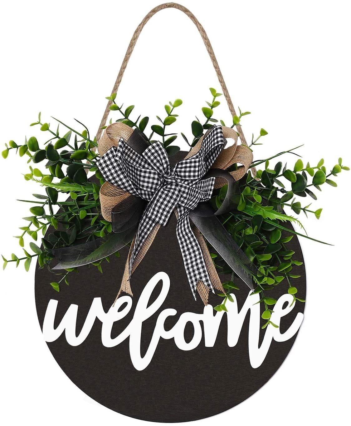 Round "Welcome" sign with a burlap bow and gingham ribbon, surrounded by unique vignettes of green leaves, suspended by a twine loop to decorate an amazing front porch.