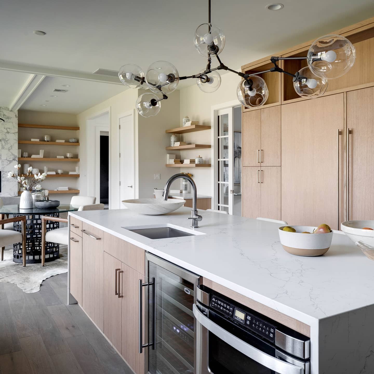 Modern kitchen featuring top 10 timeless mid-century design features, including wooden cabinetry, a white marble countertop, and a unique glass bubble chandelier.