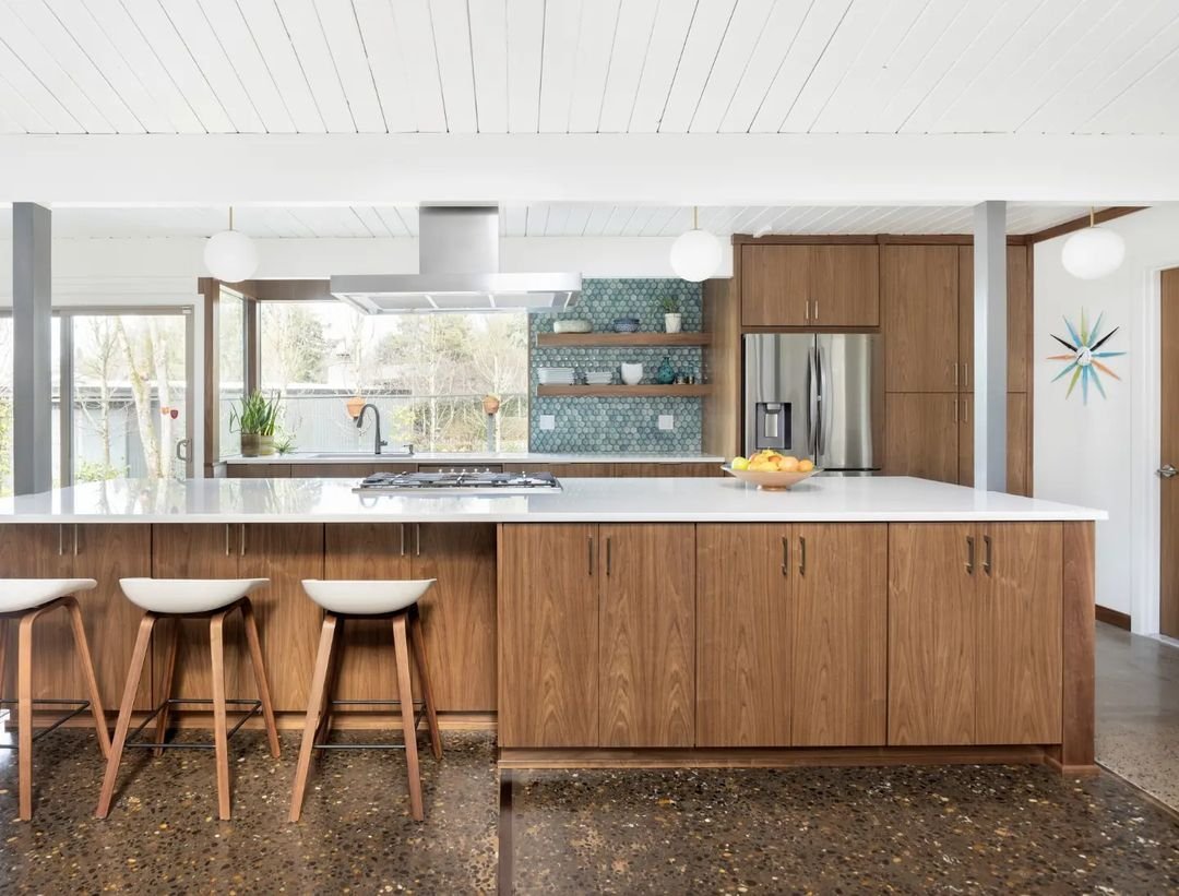Mid-Century Modern kitchen with wooden cabinets, terrazzo flooring, white ceiling, bar stools, and stainless steel appliances.