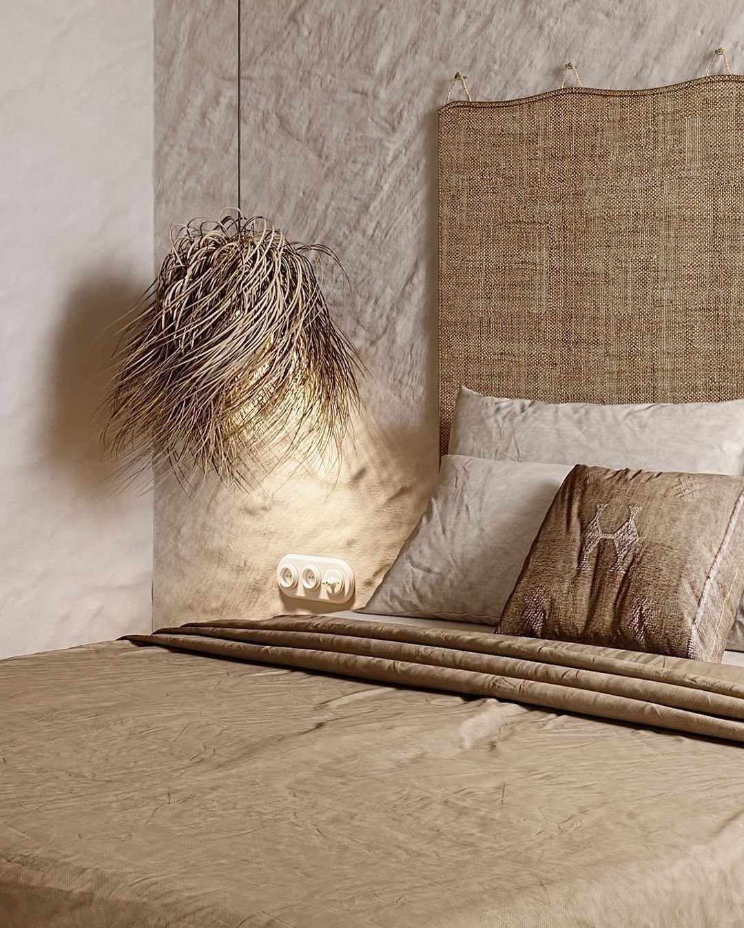 A neatly made bed with beige linens and a textured headboard exemplifies the beauty of imperfection, embracing Wabi-Sabi principles. A woven pendant light hangs beside the bed, casting a soft glow that enhances the Japandi bedroom decor.