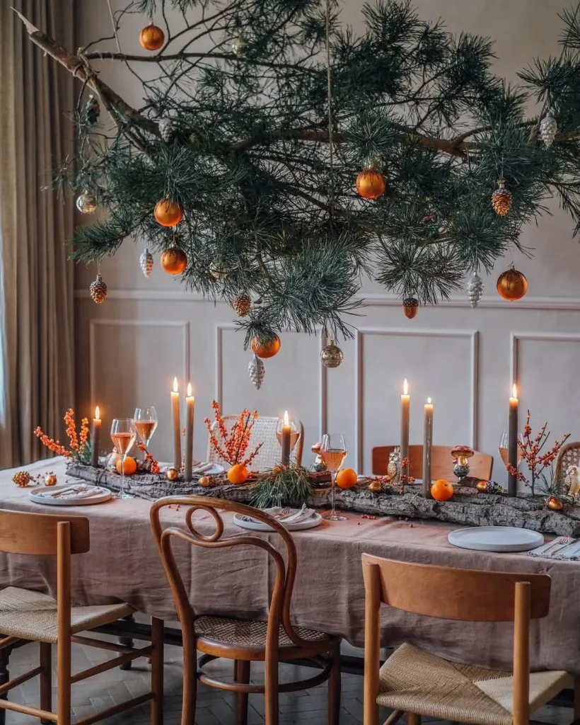 a Christmas centerpiece make of a dry tree bark with lit candle-lights, some fresh oranges, twigs, and other natural elements give this dining table a casual and warm feel