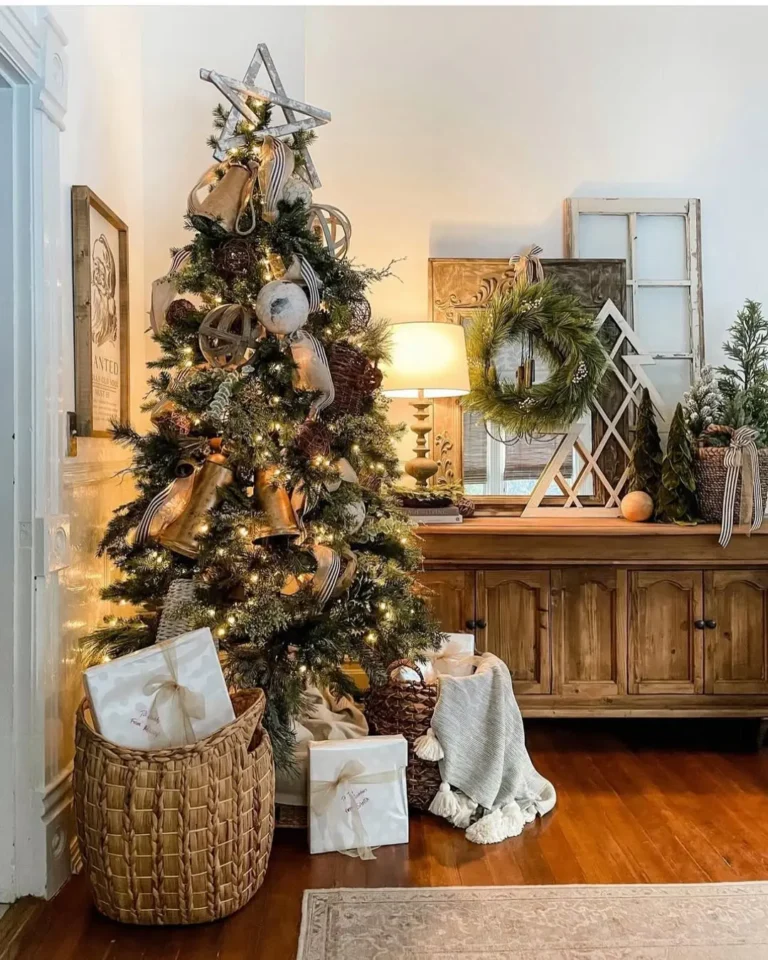 A decorated Christmas tree with lights and ribbon stands next to a wooden console table, with wrapped gifts in a basket and a wreath above—perfect inspiration for Rustic and Farmhouse Christmas Ideas: Simple Tips for Every Room.