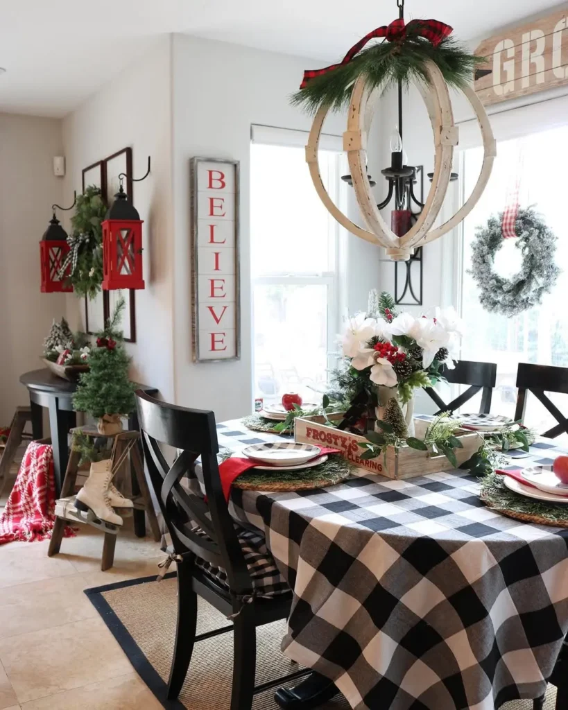 A dining room decorated for Christmas with a Buffalo Check: Black & White tablecloth, festive centerpiece, red accents, greenery, and wall signs, including one that says "BELIEVE", offers year-round home decor ideas with timeless charm.